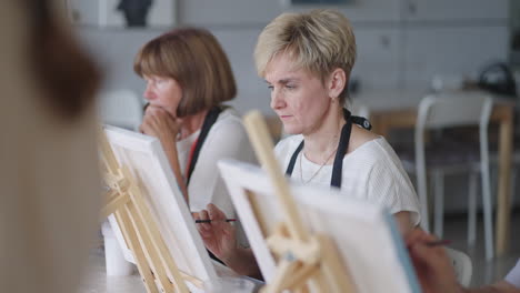 like senior friends attending together at a painting class. small group taking a variety of fun classes together. a group of elderly people attend a master class on drawing together spending time.