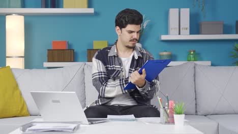 Home-office-worker-young-man-taking-notes-and-doing-calculations.