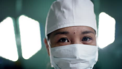 portrait of asian female surgeon wearing face mask in operating theatre at hospital, slow motion