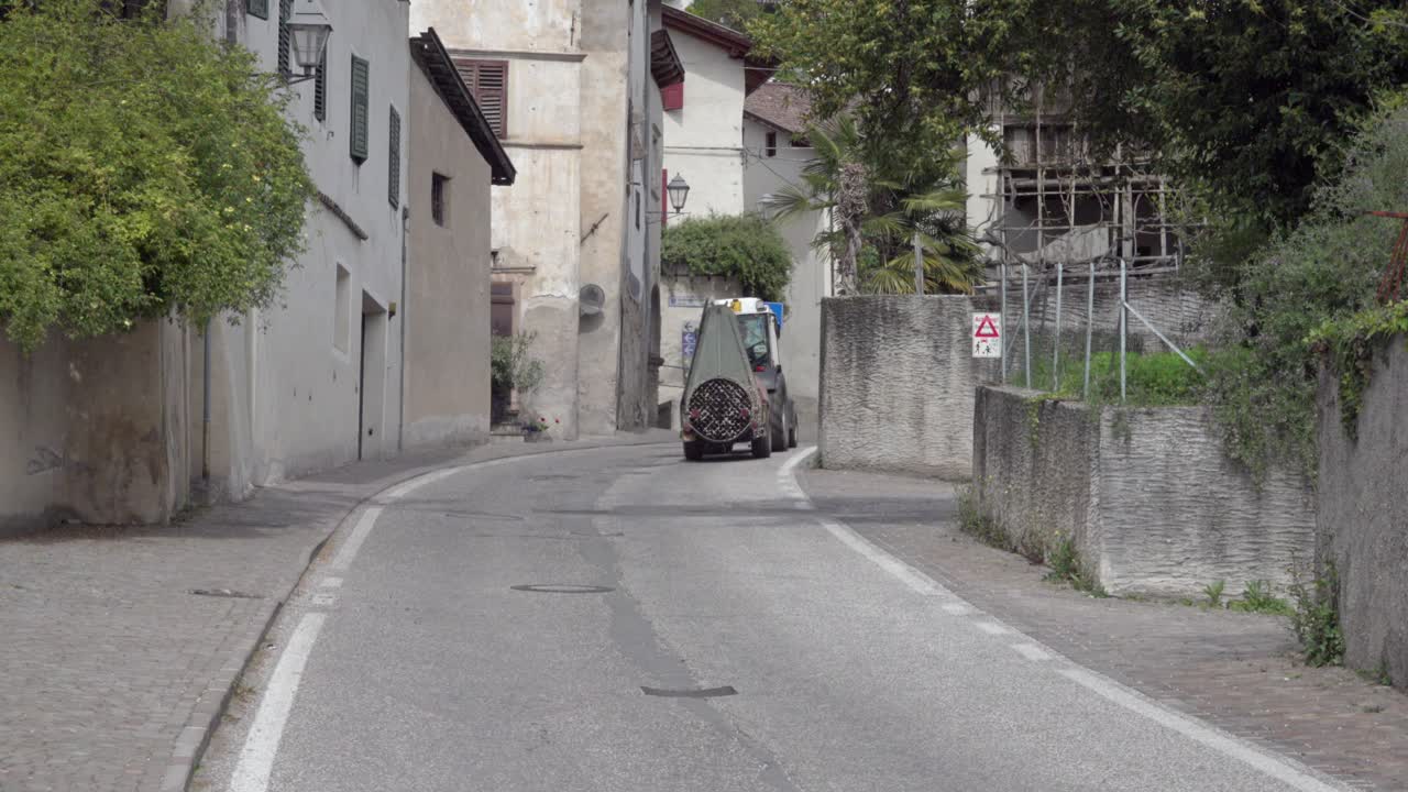 A tractor with trailer drives through the village of Kurtatsch - Cortaccia, South Tyrol, Italy