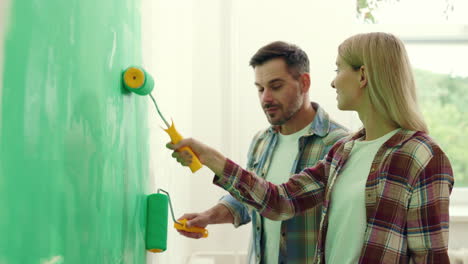 couple painting a wall green