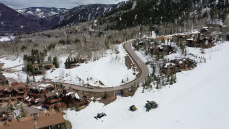 mountain skiing resort town and people sliding downhill, aerial fly over view during snowfall