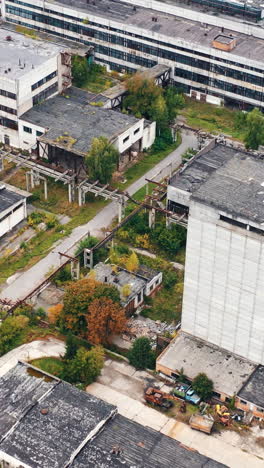 old factory background. exterior of industrial buildings of abandoned plant. empty large area with with old warehouses and tall building. aerial view.. vertical video