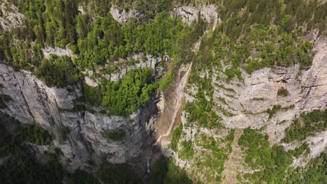 seerenbachfälle waterfall plunging down cliffs in switzerland drone view, surrounded by forest and alpine rock face
