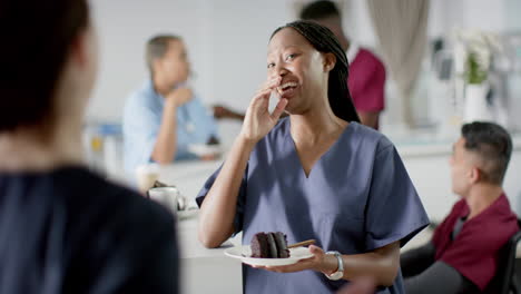 Diverse-male-and-female-doctors-eating-birthday-cake-at-reception-desk-at-hospital,-slow-motion