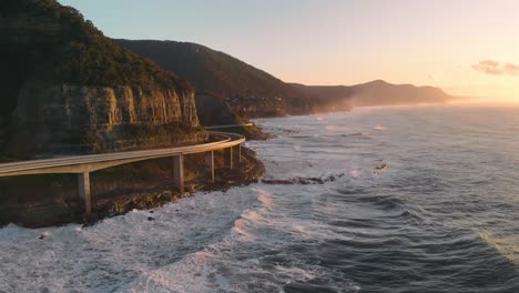 Fahrzeug-Fährt-Entlang-Meer-Klippenbrücke-Sonnenaufgang-Luftstrecke-Vorwärts---Sonnenaufgang-Australien-Ozean