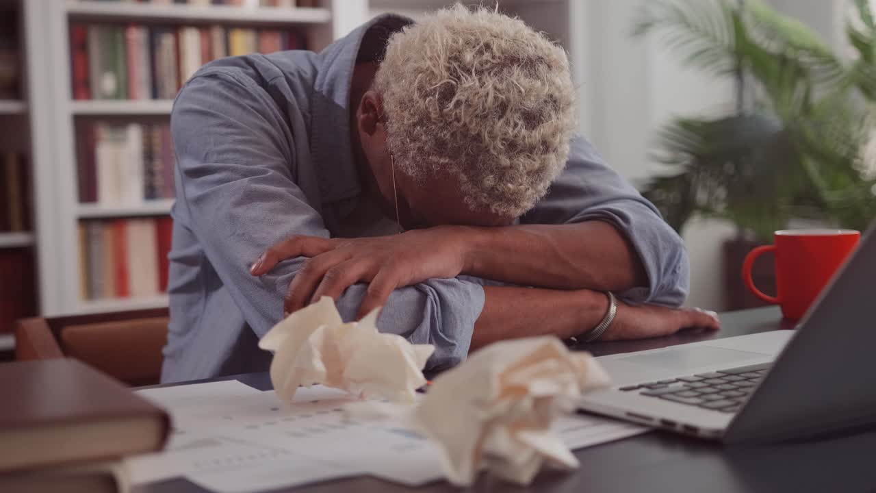 African american man put head on working table with laptop due to overwork