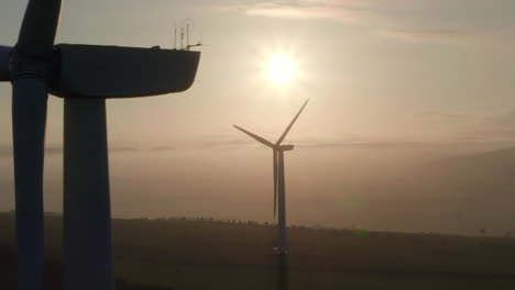 an aerial view of windfarm turbines slowly turning with the evening sun behind them, aberdeensire, scotland