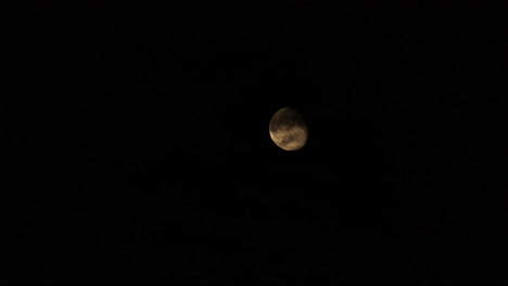 full moon comes out behind clouds in dark night sky