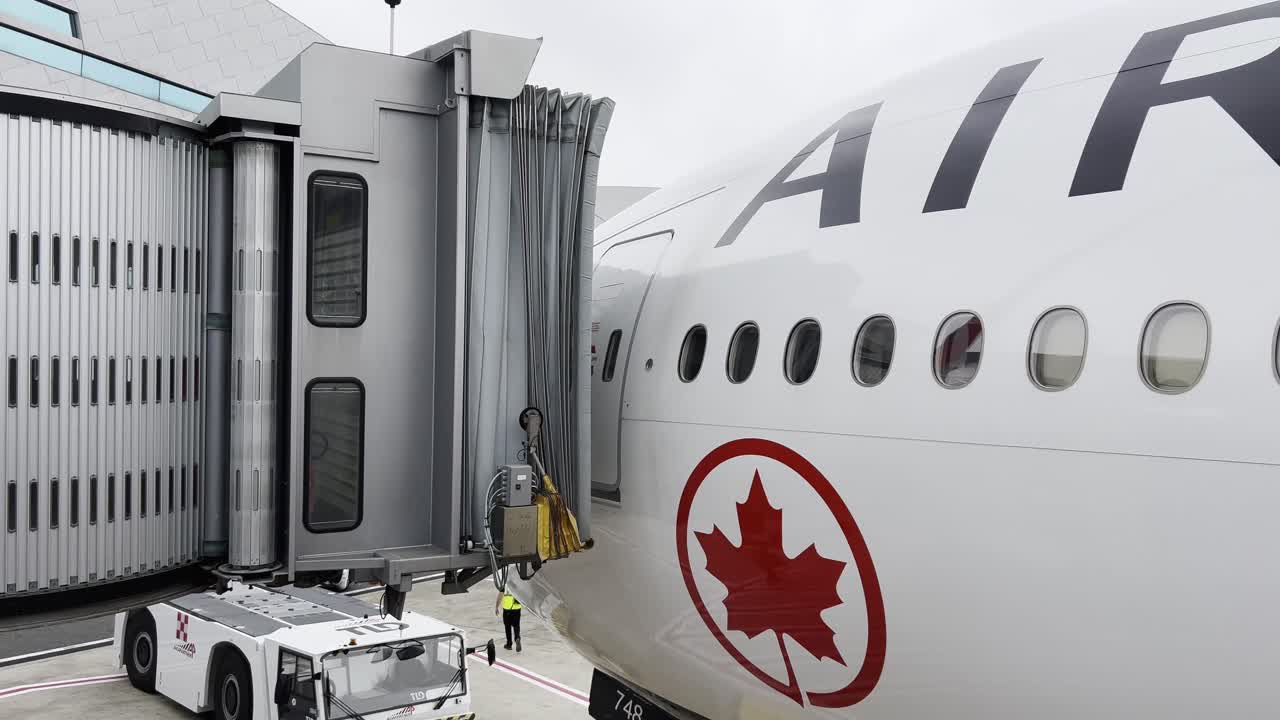 Canadian passenger airplane at airport terminal as jet bridge detaches, for final steps of ground preparations before departure