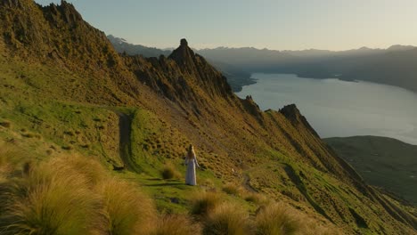 穿着优雅的衣服的女人凝视着令人惊叹的山景,海威湖,日出