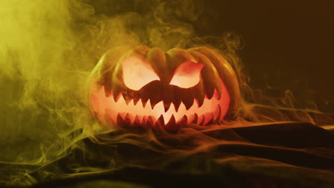 Video-of-halloween-carved-pumpkin-with-smoke-and-orange-light-on-black-background