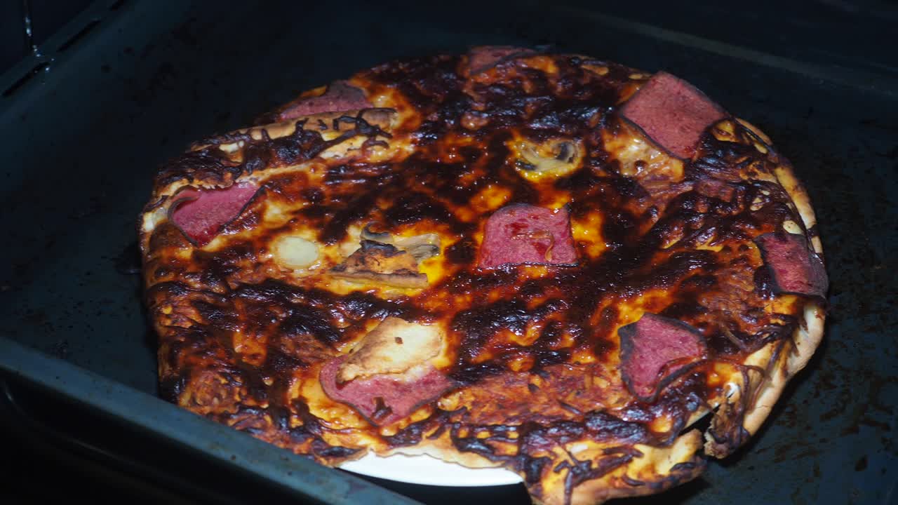 A heavily overcooked or burnt pizza in a baking tray