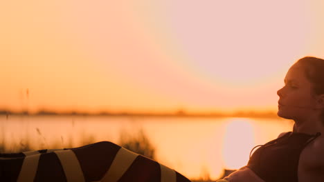 Junge-Schöne-Sportlerin,-Die-Am-Strand-Bei-Sonnenuntergang-Übungen-Für-Die-Bauchmuskulatur-Macht-Und-Sich-In-Zeitlupe-Dreht