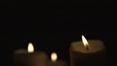 slide from left to right, and take focusing on burning candles occupy the whole area, composition on black background, take focusing from blurred, slow motion