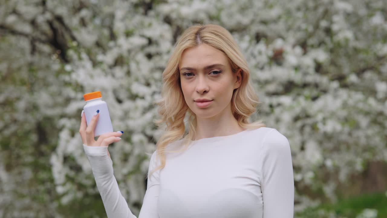 Woman holding a pill bottle in a spring garden
