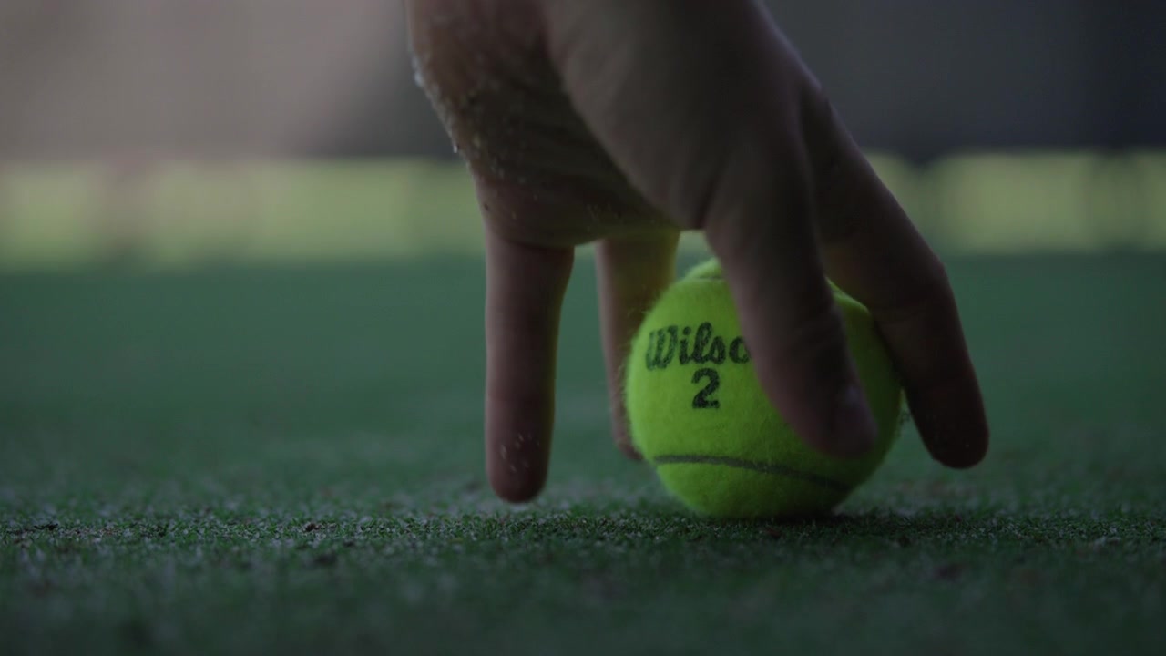 Raccogliere una palla da tennis Wilson attraverso il campo al rallentatore