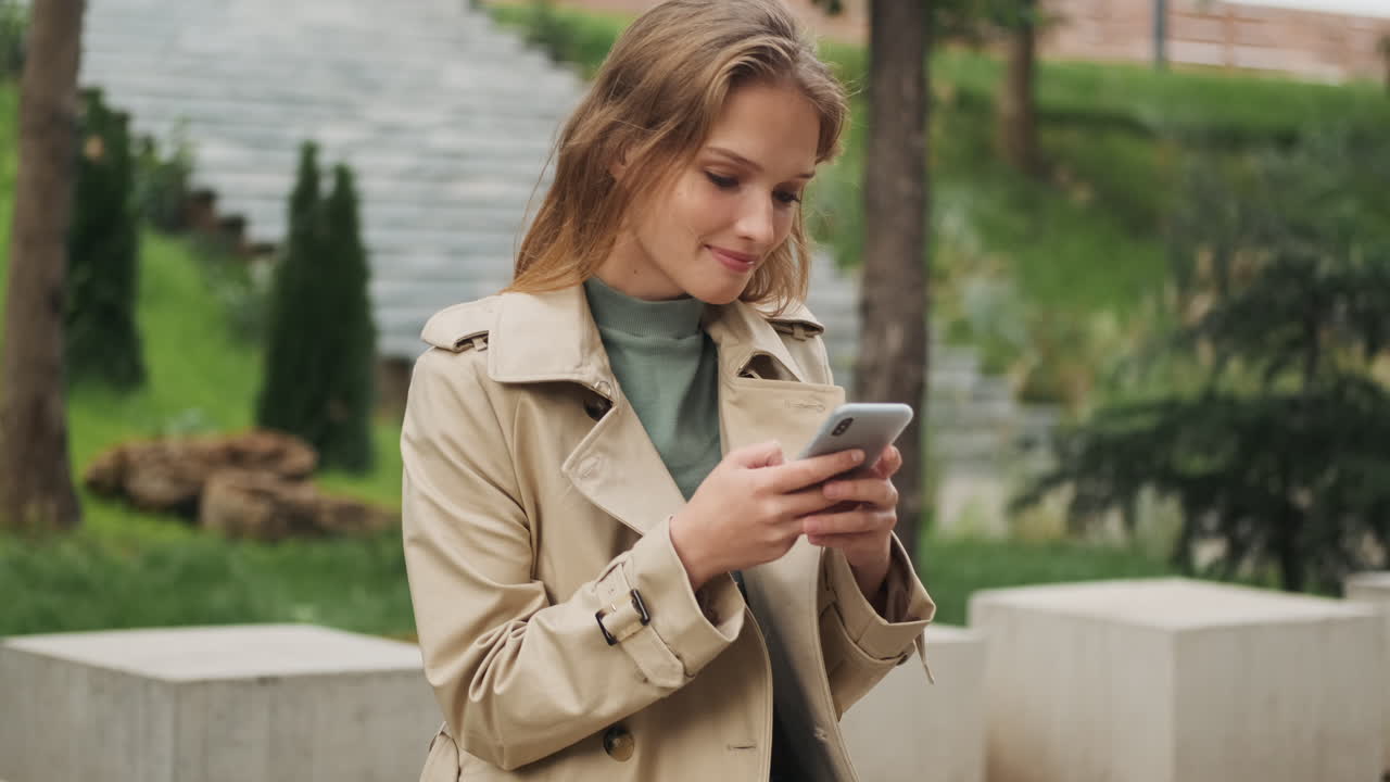 Caucasian female student using smartphone outdoors.