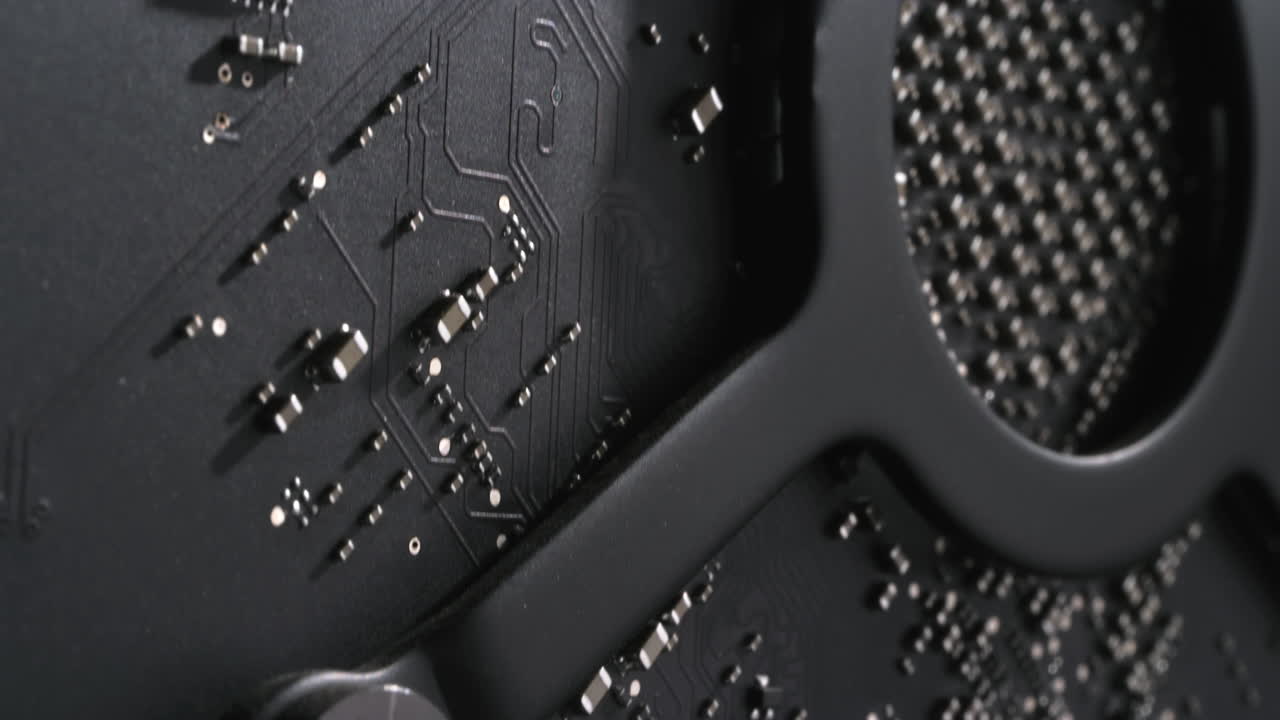 Moving up a dark high end computer's graphics card GPU, highlighting the screw of the heatsink and arriving at the capacitors. Dramatic lighting and cinematic, futuristic macro footage