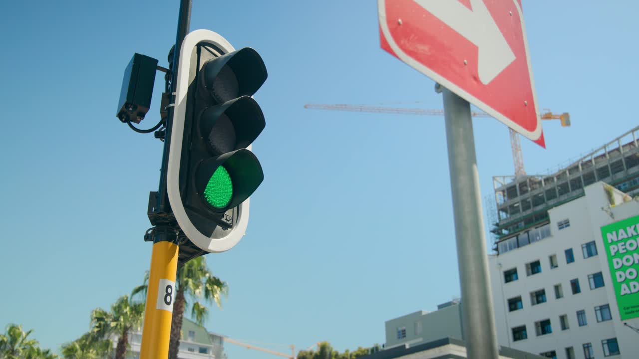 Semáforo cambiando de rojo a verde en poste amarillo, permitiendo el paso de vehículos, con espacio para texto