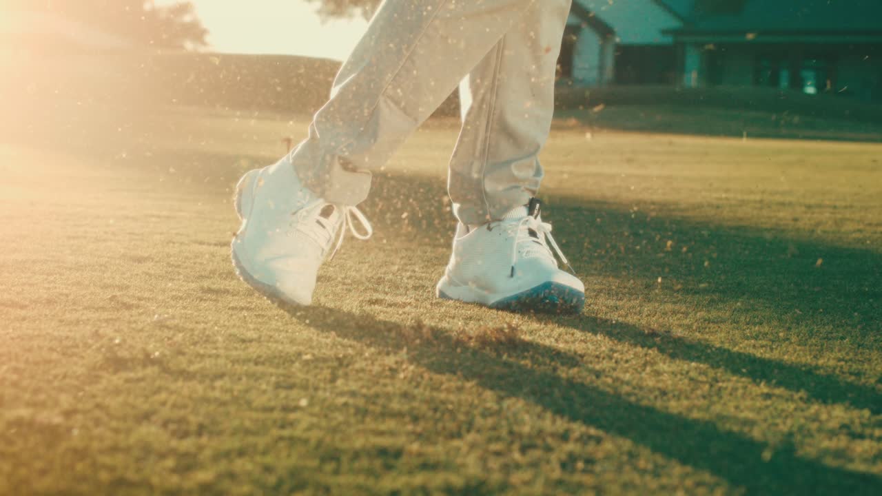 Rallentatore di scarpe da golf bianche che ruotano durante uno swing all'ora d'oro, con detriti che schizzano e una clubhouse che risplende in controluce. Perfetto per pubblicità di calzature, marketing di resort e campagne lifestyle.