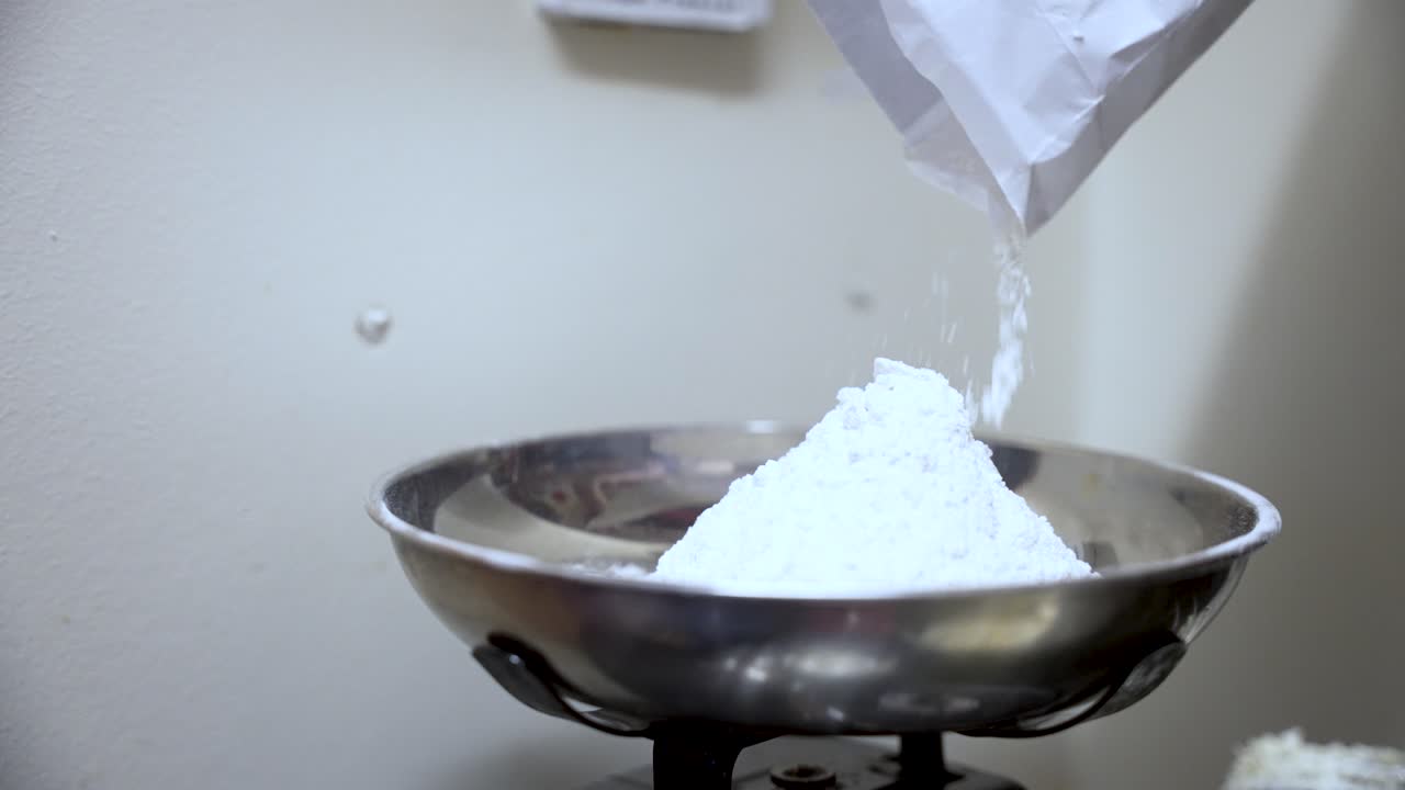 Flour poured into a steel bowl on kitchen scales highlights cooking essentials
