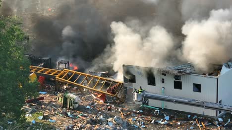 Luftaufnahme-Eines-Feuerwehrmanns,-Der-Sich-Auf-Eine-Leiter-Hebt,-Um-Einen-Brand-Im-Haus-Mit-Aufsteigendem-Rauch-Zu-Lokalisieren