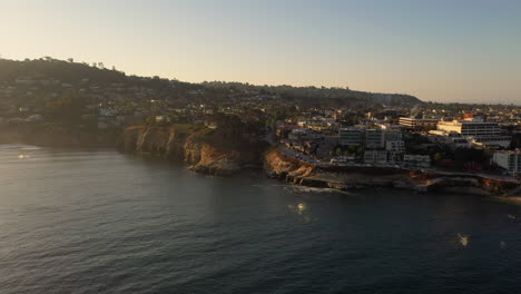 buceadores y buceadores en el agua con vistas a las cuevas marinas de la jolla después del amanecer en california - antena