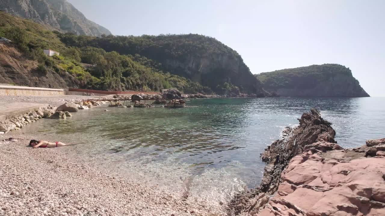 Donna snella nel suo bikini rosso sulla costa del Montenegro in una soleggiata giornata estiva
