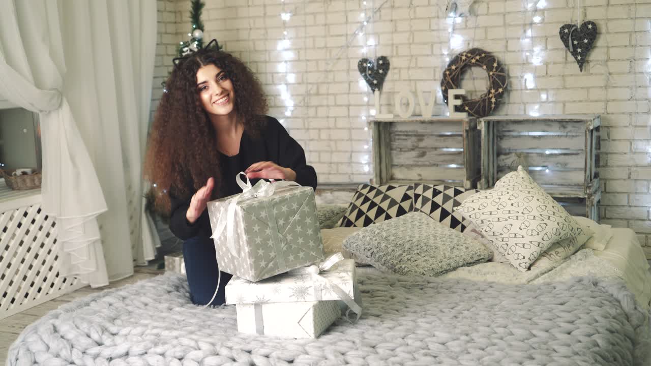 Woman opening gift boxes. Young woman with presents in New Year interior in the living room