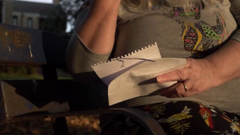 mano de mujer madura leyendo una carta en el parque primer plano