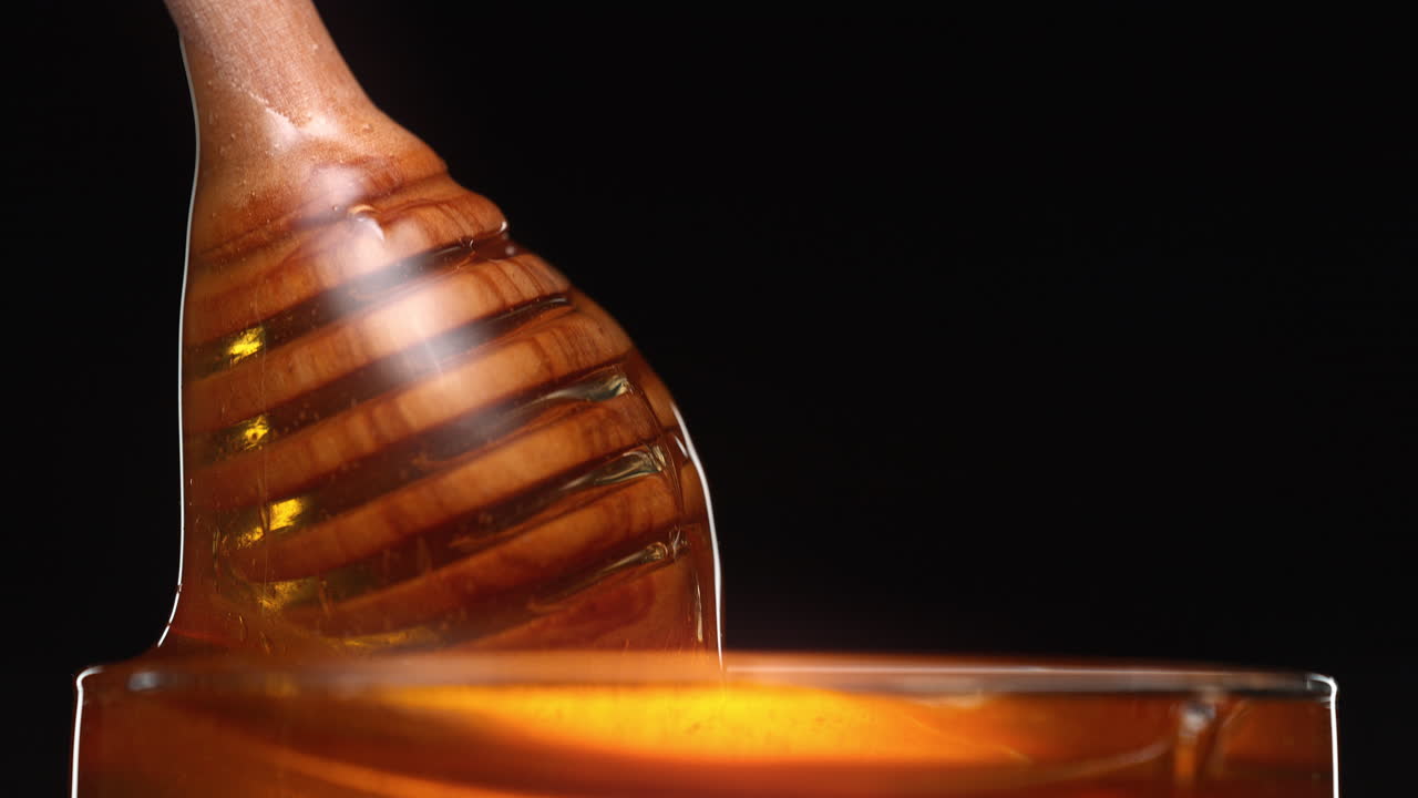 Miele che cola dal mestolo in un vaso