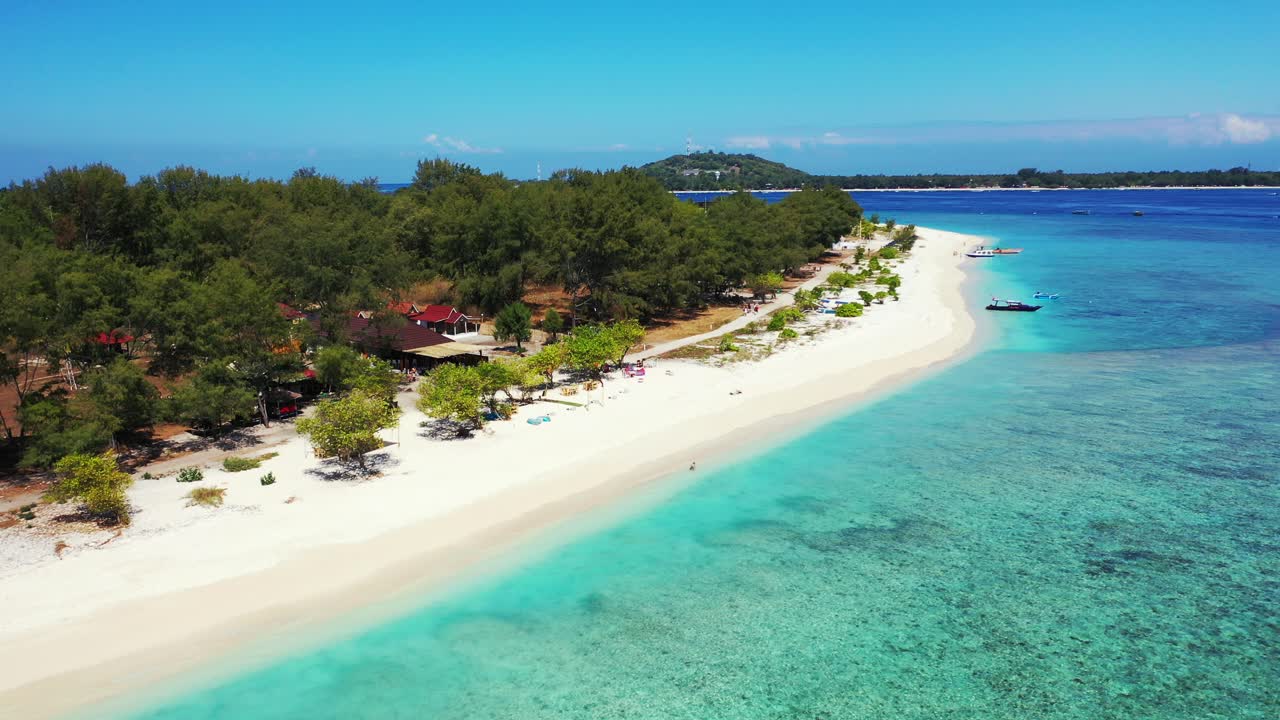 Tropical beach with white unspoiled sand and lush vegetation green trees surrounded by crystal clear water of blue turquoise sea, Gili islands, Indonesia