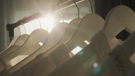 Rack-with-hangers-of-white-clothes-in-the-rays-of-the-sun-from-the-window