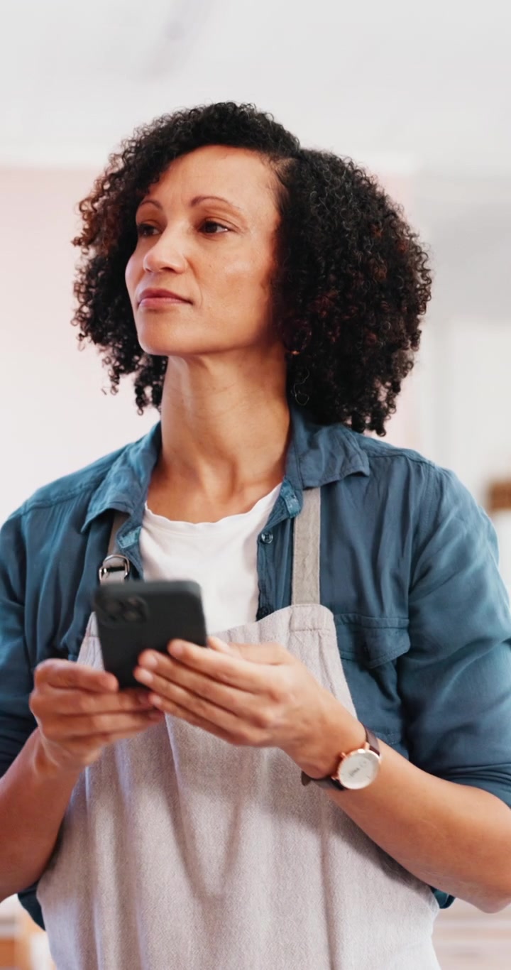 Woman Wearing Apron Using Smartphone in Kitchen