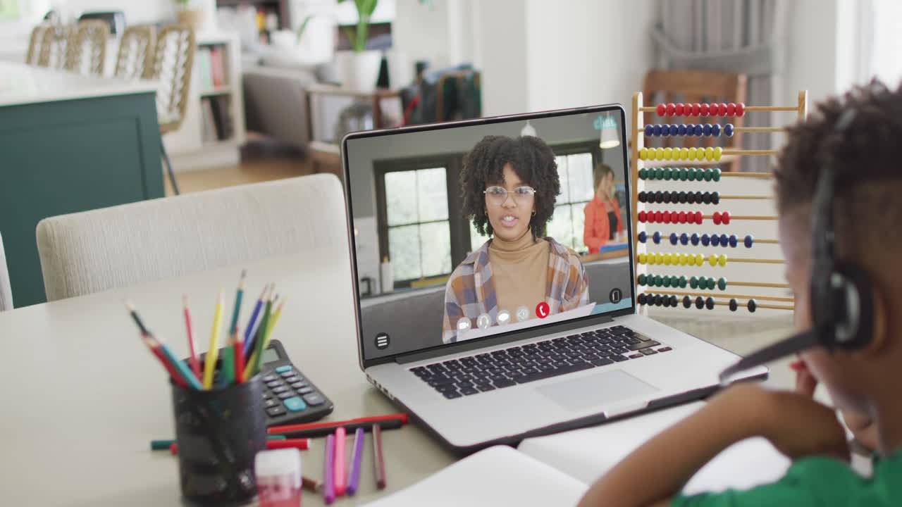 African american boy using laptop for online lesson with african american female teacher on screen
