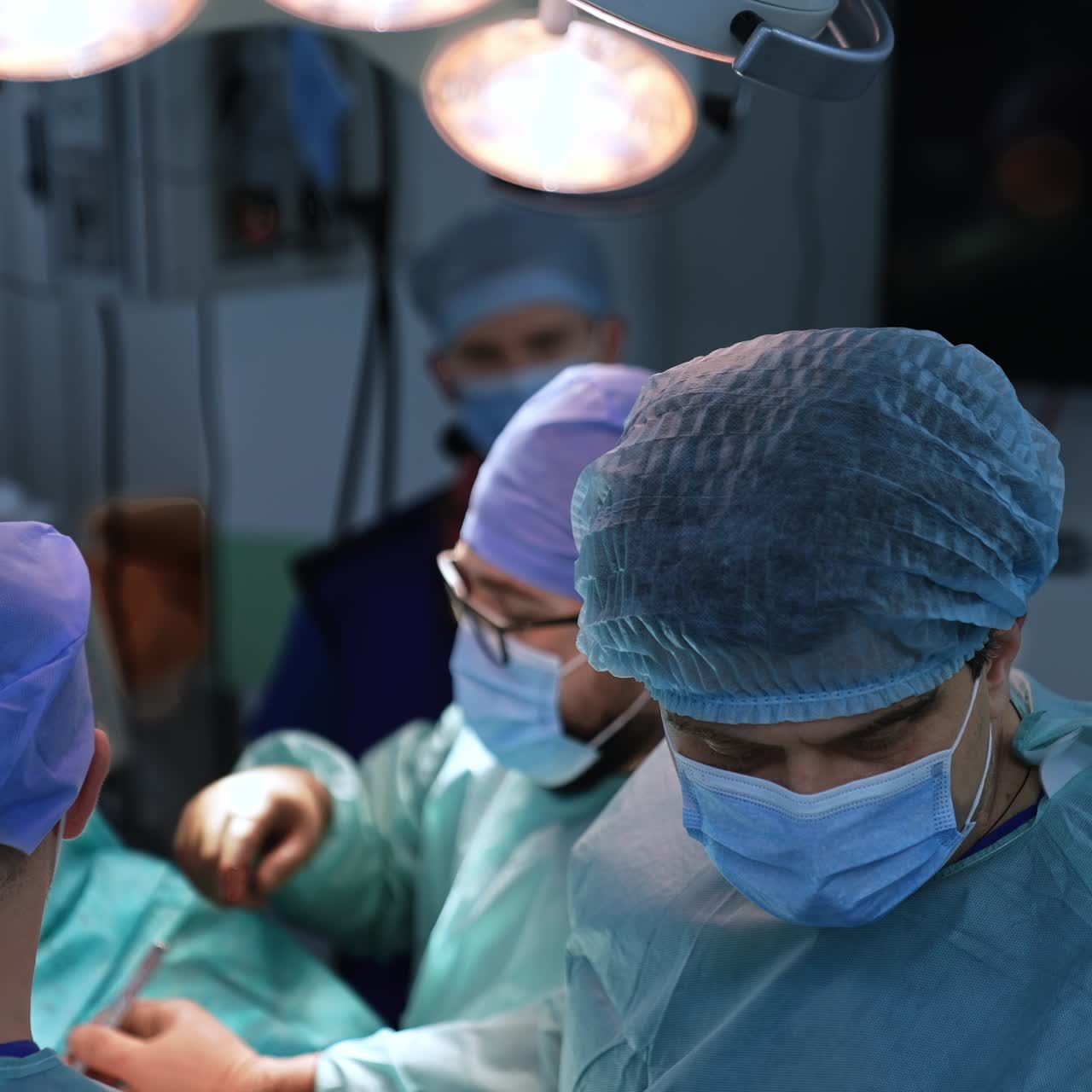 Professional doctors perform operation collaborating with each other. Male surgeons using metal tools at procedure. View from top