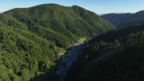 aerial tracking shot overlooking the kurama mountain town, in sunny japan