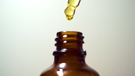 golden oil in classic rustic brown glass bottle macro close-up isolated with background beads of oil dripping out of droplet dropper