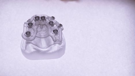 close-up of dental implant guide model held by a dentist's hands under bright light