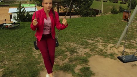 chica con chaqueta roja columpiándose en el columpio