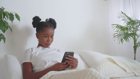 woman using smartphone in bed