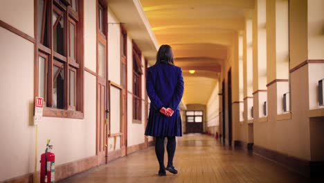 japanese high school student walks down corridor then turns and comes back