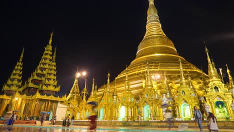 night timelapse of the golden great dagon pagoda, shwedagon, glowing on a rainy weather in yangon, myanmar