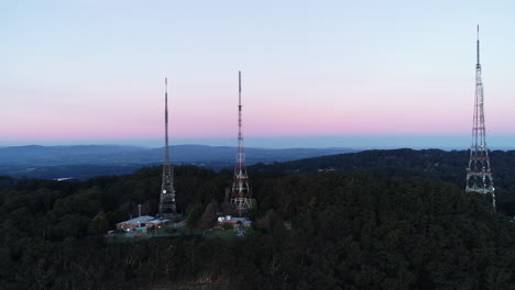 smooth aerial reveal of tv towers standing tall on mountain hill side