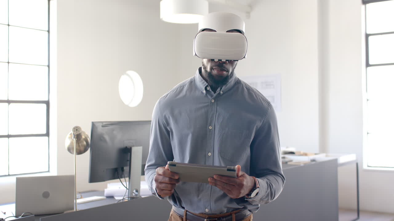 Using VR headset, businessman holding tablet in modern office environment