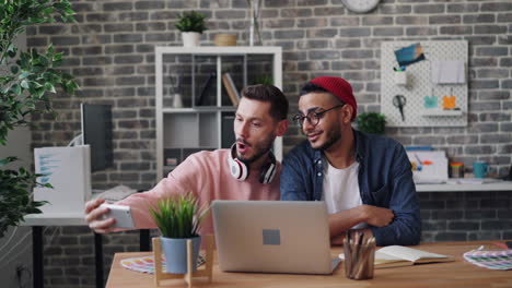 two men taking a selfie in an office environment