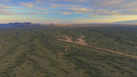 Aerial,-flat-Arizona-campground-during-dusk,-dramatic-yellow-and-orange-clouds