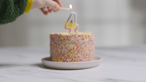 studio shot birthday cake covered with decorations and candle celebrating fourth birthday being lit