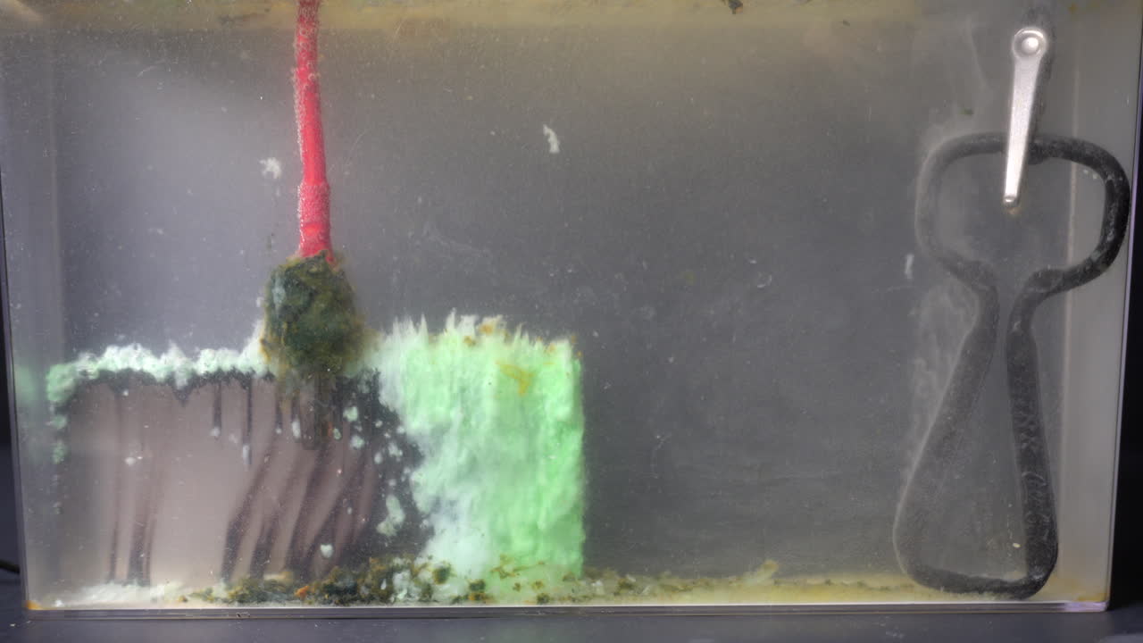 Anode mud collects on the side of the nickel plate closest to the cathode